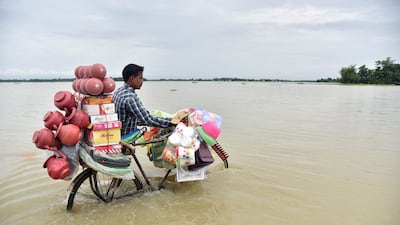 An Indian vendor pushes a bicycle carrying his wares through floodwaters in Balimukh Ashigarh village in Morigoan district, in India's northeastern state of Assam. AFP / Biju Boro