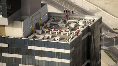 Workers line up on the edge of the Gate Tower before beginning their descent. Christopher Pike / The National