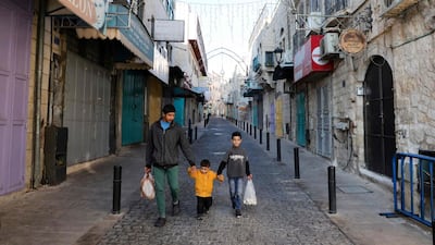 Children walk in front of shuttered shops in a street decorated for Christmas in the biblical city of Bethlehem in the occupied West Bank. AFP