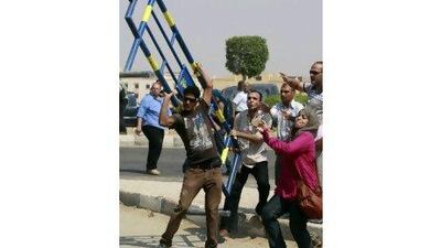 An anti-Mubarak demonstrator lifts a barrier before throwing it towards riot police during clashes in front of the police academy where the trial of Hosni Murbarak resumed yesterday. Amr Abdallah Dalsh / Reuters