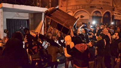 Lebanese anti-government protesters carry a security booth amid clashes with the army in the northern port city of Tripoli. AFP