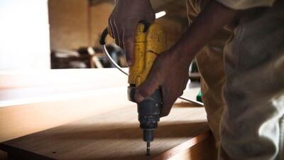 A man drills the remaining nails into the wood to seal off a coffin.