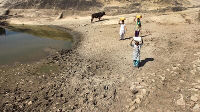 Women carry containers to collect drinking water from an almost dried up well at Talad village near Jammu. Channi Anand / AP Photo