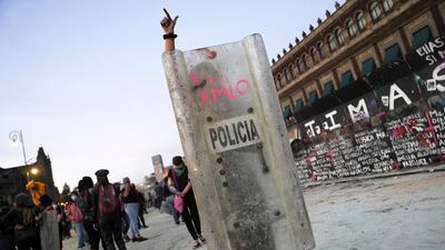 A woman gestures behind a shield reading "AMLO Out" during a protest outside the National Palace on International Women's Day in Mexico City, Mexico. Reuters