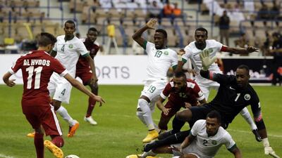 Qatar’s Hassan Al-Hydos (L) takes a shot at goal as Saudi national team players defend during the opening match of the 22nd Gulf Cup football tournament at the King Fahd Stadium in Riyadh on November 13, 2014. Eight nations are taking part in the games including Oman, UAE, Kuwait, Yemen, Bahrain, Iraq, Saudi Arabia and Qatar. AFP PHOTO/KARIM SAHIB