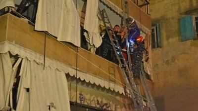 Members of Lebanese Civil Defence evacuate a woman from her apartment after a fuel tank exploded in Beirut's Tariq al-Jdide neighbourhood. AFP