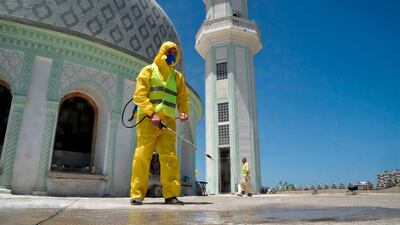 A civil volunteer from the Hocine Dey commune sprays disinfectant on the roof by the dome of the Abou Hanifa Enouemane mosque in the capital Algiers, Algeria. AFP