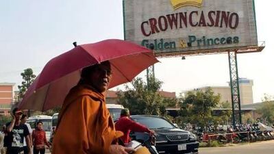 A Cambodian Buddhist monk takes morning alms next to a casino signboard in Poipet, Cambodia. Football betting is illegal in Cambodia, but visitors to this seedy frontier town wouldn't know it.