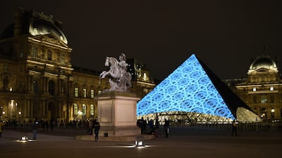 The dome pattern of the Louvre Abu Dhabi is projected onto the Louvre Pyramid in Paris on Wednesday night. Eric Feferberg / AFP