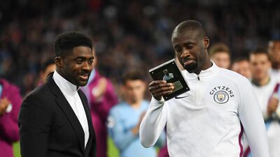Manchester City's Yaya Toure looks at a gift as his brother Kolo Toure watches on. Gareth Copley / Getty Images