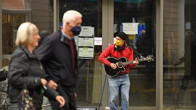 A busker plays a guitar while wearing a face mask in Sheffield. AFP