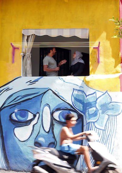 Ayad Nasser, the property developer behind the Ouzville project, speaks with a woman inside her repainted house in Beirut's southern Ouzai neighbourhood, AFP