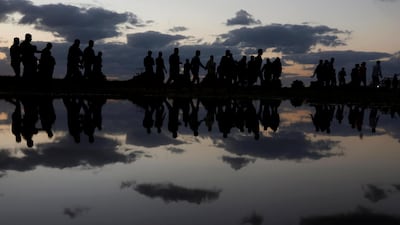Palestinian demonstrators are reflected in rain water after attending a protest. Reuters