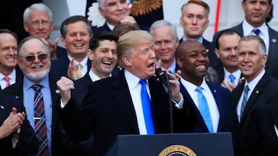 FILE - In this Dec. 20, 2017, file photo, House Speaker Paul Ryan of Wis., back left center, and other lawmakers react as President Donald Trump speaks about the passage of the tax overhaul bill on the South Lawn at the White House in Washington. Manuel Balce Ceneta / AP