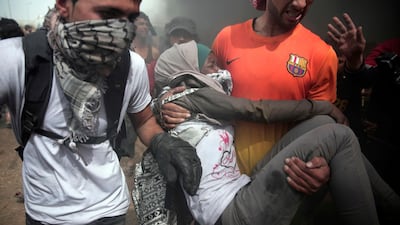 A wounded woman is carried away during protests against a crippling blockade at the Gaza Strip's border with Israel. Khalil Hamra / AP