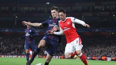 Paris Saint-Germain's Belgian defender Thomas Meunier, left, challenges Arsenal's German midfielder Mesut Ozil during their Uefa Champions League match. Ian Kington / AFP