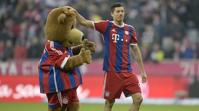 Bayern Munich’s Polish striker Robert Lewandowski plays with the maskot after the German first division Bundesliga football match FC Bayern Munich vs Hamburger SV at the Allianz Arena in Munich, southern Germany, on February 14, 2015. AFP PHOTO / CHRISTOF STACHE