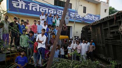 Onlookers watch as rescuers lift upturned coaches of the Kalinga-Utkal Express. Altaf Qadri / The Associated Press
