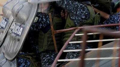 Police shelter from missiles thrown at them during a protest in Buenos Aires, Argentina, against the death of Morena Dominguez, 11, who died from her injuries after criminals tried to rob her. AP