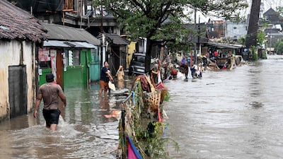 Residents wade through floodwater after heavy rain in Denpasar, on the Indonesian island of Bali. AFP