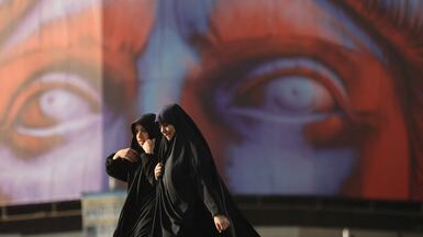 Iranian women walk past an anti-US billboard on a street in Tehran. Reuters