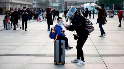 A woman adjusts her child's mask as they arrive at Hankou Railway Station in Wuhan. AFP