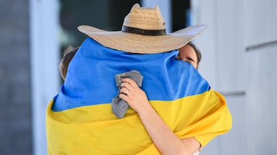 A man wrapped in a Ukrainian flag embraces a refugee in southern California. AFP