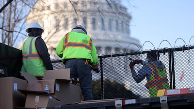 Workers install razor wire atop the unscalable fence surrounding the US Capitol. Reuters