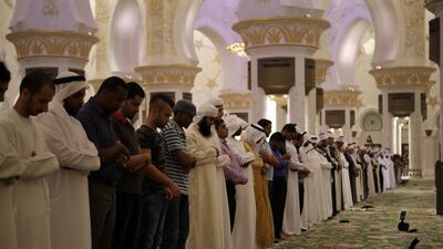 Men stand for prayer after breaking their fasts in Sheikh Zayed Mosque on the first day of Ramadan. Ravindranath K / The National