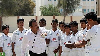 A coach with the Abu Dhabi Indian school Under 16 Cricket team goes over how to deliver a certain spin on things during their practice session at their school ground in Abu Dhabi.