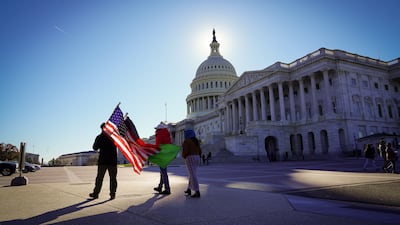 Protesters walk in front of the US Capitol flying Afghan and US flags