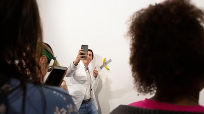 A man poses for a photo next to a banana attached with duct-tape that replaces the artwork 'Comedian' by the artist Maurizio Cattelan, which was eaten by David Datuna, in Miami Beach, Florida, December 7, 2019. Reuters