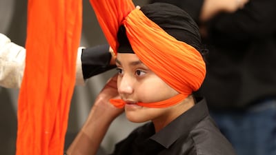 A young member of the Sikh community gets his turban prepared for the party.