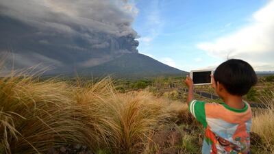 A boy takes pictures during Mount Agung's eruption seen from Kubu sub-district in Karangasem Regency on Indonesia's resort island of Bali. Mount Agung belched smoke as high as 1,500 metres above its summit, sparking an exodus from settlements near the mountain. Sonny Tumbelaka / AFP