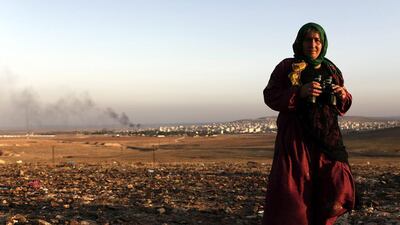 A woman holds a pair of binoculars while watching the fighting between Syrian Kurdish fighters and ISIL militants in Kobani from the Turkish side of the border. Sedat Suna / EPA