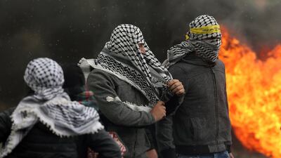 Palestinian protesters seek cover during clashes with Israeli forces. EPA