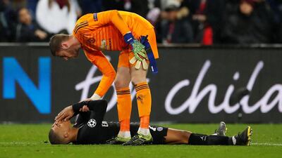 PSG forward Kylian Mbappe looks dejected as Manchester United's David de Gea stands over him after the match. Reuters