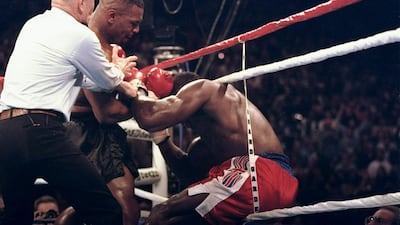 Mike Tyson lands punches and backs Frank Bruno into the ropes as referee Mills Lane steps in to stop the fight during the third round