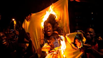 A citizen burns a shirt of the Zimbabwe's ruling party, ZANU PF, as hundreds celebrate the resignation of president Robert Mugabe in Johannesburg, South Africa. Wikus De Wet / AFP Photo