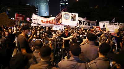 Police force stand in front of the protestors as they block a main junction in the city following a protest against the government's response to the financial fallout of the coronavirus disease (COVID- 19) crisis in Tel Aviv. REUTERS