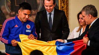 Colombia's President Ivan Duque, right, gives the Colombian national flag to national team captain Radamel Falcao at Narino Presidential Palace in Bogota, on June 4, 2019 ahead of the the 2019 Copa America in Brazil. AFP