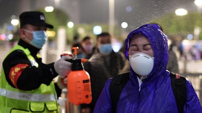 A police officer sprays disinfectant on a traveller outside Hankou Railway Station after travel restrictions to leave Wuhan were lifted. Reuters