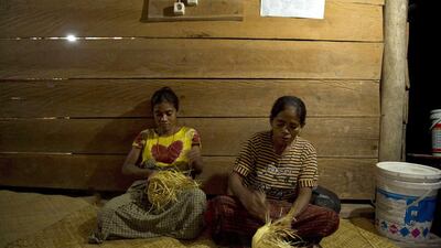 Sumbanese women weave baskets under a lamp powered by electricity from mini-hydroelectric generators built beside a river dam in Kamanggih village. Romeo Gacad / AFP