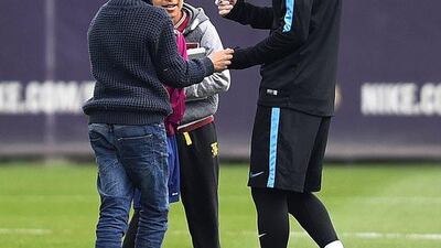 Lionel Messi of FC Barcelona signs his autograph for young fans who ran onto the training pitch during a Barcelona training session ahead of the Uefa Champions League round of 16 second leg match between Barcelona and Arsenal at Ciutat Esportiva on March 15, 2016 in Barcelona, Spain. (Photo by David Ramos/Getty Images)