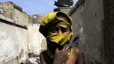 A Filipino boy collects salvageable materials among debris following an overnight fire that razed a slum area in Caloocan city, east of Manila, the Philippines. Francis Malasig / EPA