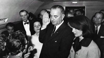 Lyndon B Johnson is sworn in as the 36th president of the United States on board Air Force One, after the assassination of President John F Kennedy. His wife, Lady Bird, left, and the grief-stricken first lady, Jackie Kennedy, look on. Keystone / Getty Images