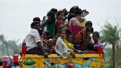 Indian villagers ride on the back of a tractor bearing a picture of Hindu monkey god Lord Hanuman as they return to Sonupur village after being evacuated during the approach of Cyclone Phailin. Manan Vatsyayana / AFP