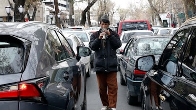 An Iranian man plays music among the cars to collect money during Norwuz. EPA