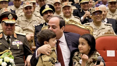 Egyptian President Abdel Fattah El Sisi kisses a child of a fallen soldier during a conference commemorating the country's martyrs in Cairo on March 15, 2018. Mohammed Samaha / Egyptian Presidency via AP