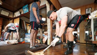 Canadian player Peter Nelson, right, volunteers to clean up mud in a house in Kamaishi, Iwate prefecture, Japan, following the cancellation of their Rugby World Cup Pool B match against Namibia due to Typhoon Hagibis. AP